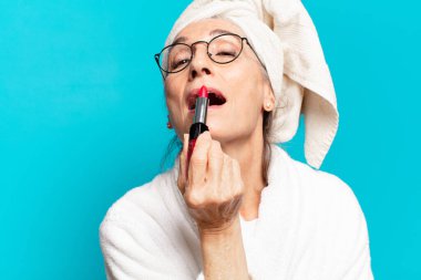 Duştan sonra giyinmiş, makyajlı ve bornozlu hoş bir kadın.