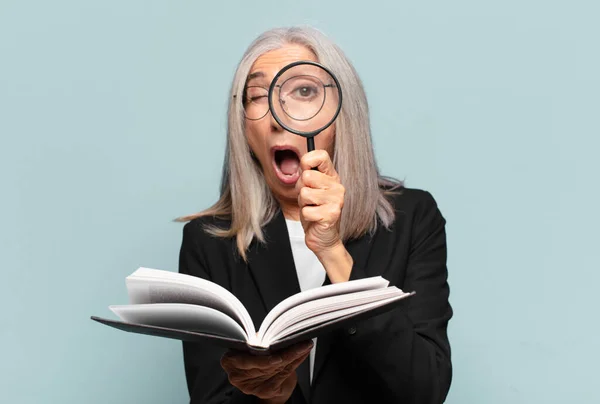 本と虫眼鏡をかけた年配の可愛い女性 検索の概念 — ストック写真