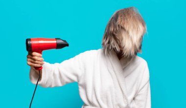 Duştan sonra bornoz giyen yaşlı ve güzel bir kadın. Saç kurutma makinesi konsepti