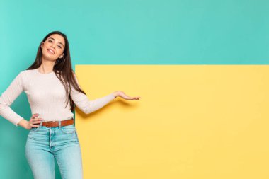 Genç, güzel bir kadın kendini mutlu ve neşeli hissediyor, gülümsüyor ve seni hoş karşılıyor, dostça bir jestle içeri davet ediyor. Konseptinizi yerleştirmek için boşluk kopyalayın