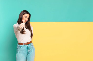 Genç, güzel bir kadın gururlu, tasasız, kendinden emin ve mutlu, başparmağıyla olumlu gülümsüyor. Konseptinizi yerleştirmek için boşluk kopyalayın