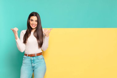 Genç ve güzel bir kadın neşeyle gülümsüyor ve mutlu görünüyor, tasasız ve pozitif hissediyor. Konseptinizi yerleştirmek için boşluk kopyalayın