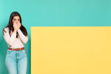 Genç, güzel bir kadın endişeli, gergin, stresli ve korkmuş görünüyor tırnaklarını yiyor ve yanal fotokopi için yer arıyor. Konseptinizi yerleştirmek için boşluk kopyalayın