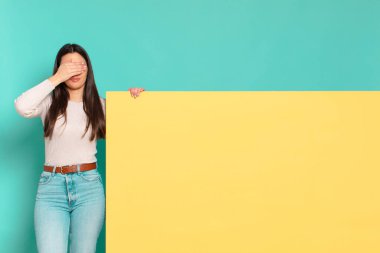 Genç ve güzel bir kadın tek eliyle gözlerini kapatıyor korkmuş ya da endişeli hissediyor, merak ediyor ya da körü körüne bir sürpriz bekliyor. Konseptinizi yerleştirmek için boşluk kopyalayın