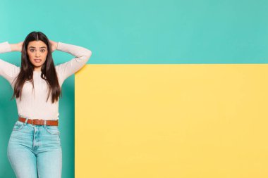 Genç, güzel bir kadın kendini stresli, endişeli, endişeli ya da korkmuş hissediyor. Elleri başının üstünde, hatayla panikliyor. Konseptinizi yerleştirmek için boşluk kopyalayın