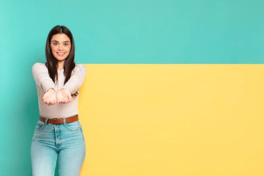 Genç, güzel bir kadın mutlu bir şekilde gülümsüyor. Dost canlısı, kendine güvenen, olumlu bakışlı, bir nesne ya da konsept sunuyor. Konseptinizi yerleştirmek için boşluk kopyalayın