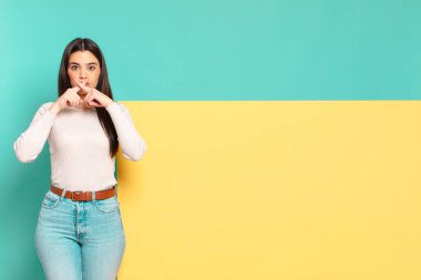 young pretty woman looking serious and displeased with both fingers crossed up front in rejection, asking for silence. copy space to place your concept