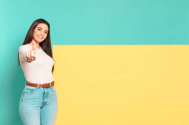 young pretty woman smiling proudly and confidently making number one pose triumphantly, feeling like a leader. copy space to place your concept