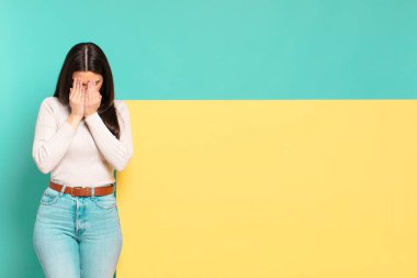 young pretty woman feeling sad, frustrated, nervous and depressed, covering face with both hands, crying. copy space to place your concept