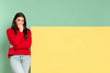 young pretty woman feeling serious, thoughtful and concerned, staring sideways with hand pressed against chin. copy space to place your concept