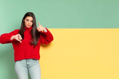 young pretty woman feeling confused, clueless and unsure, weighting the good and bad in different options or choices. copy space to place your concept