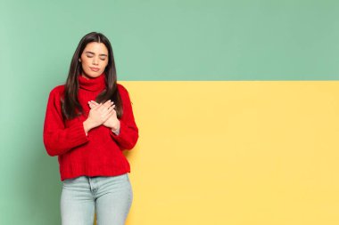 young pretty woman looking sad, hurt and heartbroken, holding both hands close to heart, crying and feeling depressed. copy space to place your concept