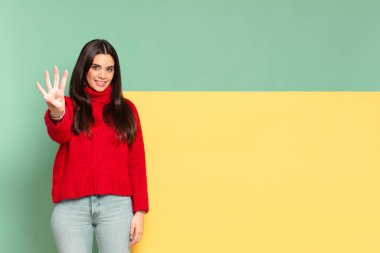young pretty woman smiling and looking friendly, showing number four or fourth with hand forward, counting down. copy space to place your concept