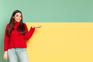 young pretty woman smiling cheerfully, feeling happy and showing a concept in copy space with palm of hand. copy space to place your concept