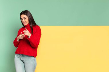 young pretty woman feeling happy, cool, satisfied, relaxed and successful, pointing at camera, choosing you. copy space to place your concept