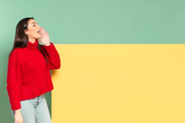 young pretty woman profile view, looking happy and excited, shouting and calling to copy space on the side. copy space to place your concept
