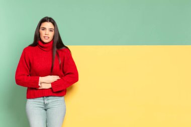 young pretty woman feeling anxious, ill, sick and unhappy, suffering a painful stomach ache or flu. copy space to place your concept