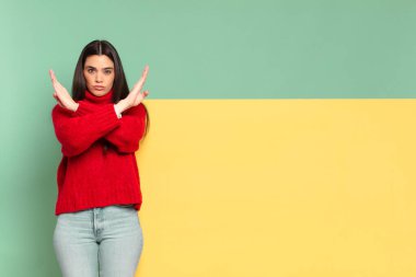 young pretty woman looking annoyed and sick of your attitude, saying enough! hands crossed up front, telling you to stop. copy space to place your concept