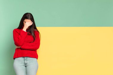 young pretty woman looking stressed, ashamed or upset, with a headache, covering face with hand. copy space to place your concept