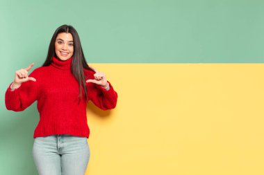 young pretty woman framing or outlining own smile with both hands, looking positive and happy, wellness concept. copy space to place your concept