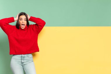 young pretty woman looking excited and surprised, open-mouthed with both hands on head, feeling like a lucky winner. copy space to place your concept