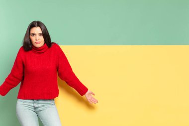 young pretty woman feeling clueless and confused, having no idea, absolutely puzzled with a dumb or foolish look. copy space to place your concept