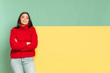 young pretty woman looking like a happy, proud and satisfied achiever smiling with arms crossed. copy space to place your concept