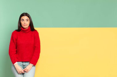 young pretty woman looking puzzled and confused, wondering or trying to solve a problem or thinking. copy space to place your concept