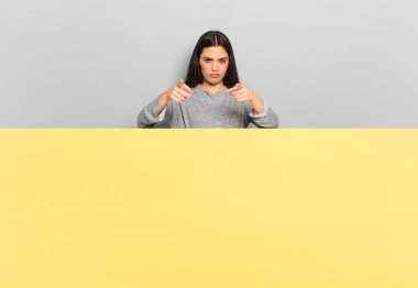 young pretty woman pointing forward at camera with both fingers and angry expression, telling you to do your duty. copy space to place your concept