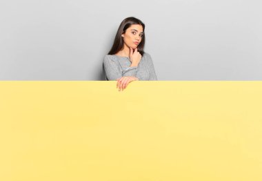 young pretty woman looking serious, confused, uncertain and thoughtful, doubting among options or choices. copy space to place your concept