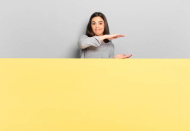 young pretty woman holding an object with both hands on side copy space, showing, offering or advertising an object. copy space to place your concept