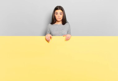 young pretty woman looking puzzled and confused, biting lip with a nervous gesture, not knowing the answer to the problem. copy space to place your concept