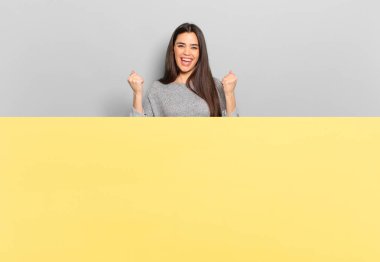 young pretty woman shouting triumphantly, laughing and feeling happy and excited while celebrating success. copy space to place your concept