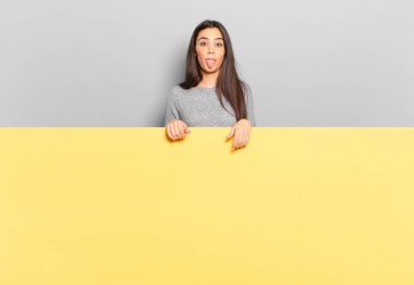 young pretty woman feeling disgusted and irritated, sticking tongue out, disliking something nasty and yucky. copy space to place your concept