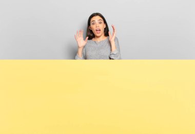 young pretty woman screaming with hands up in the air, feeling furious, frustrated, stressed and upset. copy space to place your concept