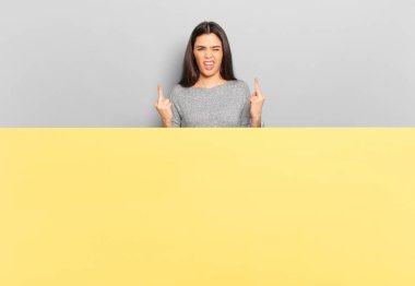 young pretty woman feeling provocative, aggressive and obscene, flipping the middle finger, with a rebellious attitude. copy space to place your concept