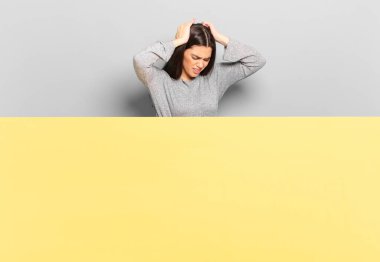 young pretty woman feeling stressed and frustrated, raising hands to head, feeling tired, unhappy and with migraine. copy space to place your concept