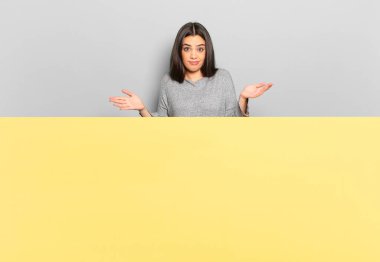 young pretty woman feeling puzzled and confused, unsure about the correct answer or decision, trying to make a choice. copy space to place your concept