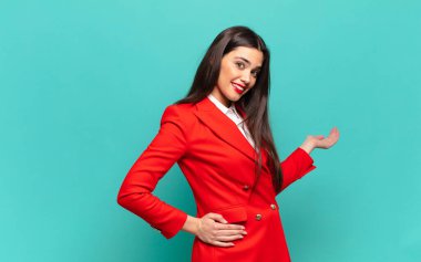 young pretty woman feeling happy and cheerful, smiling and welcoming you, inviting you in with a friendly gesture. business concept