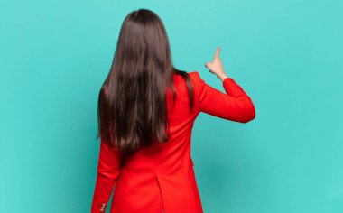 young pretty woman standing and pointing to object on copy space, rear view. business concept