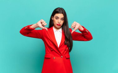 young pretty woman looking sad, disappointed or angry, showing thumbs down in disagreement, feeling frustrated. business concept