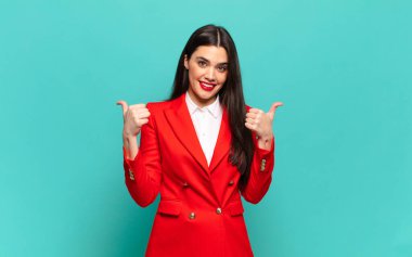 young pretty woman smiling joyfully and looking happy, feeling carefree and positive with both thumbs up. business concept