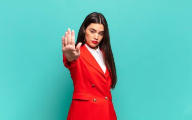 young pretty woman looking serious, stern, displeased and angry showing open palm making stop gesture. business concept