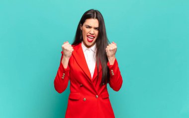 young pretty woman shouting aggressively with annoyed, frustrated, angry look and tight fists, feeling furious. business concept