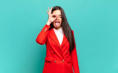 young pretty woman smiling happily with funny face, joking and looking through peephole, spying on secrets. business concept