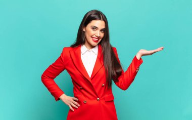 young pretty woman smiling, feeling confident, successful and happy, showing concept or idea on copy space on the side. business concept