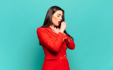 young pretty woman feeling ill with a sore throat and flu symptoms, coughing with mouth covered. business concept