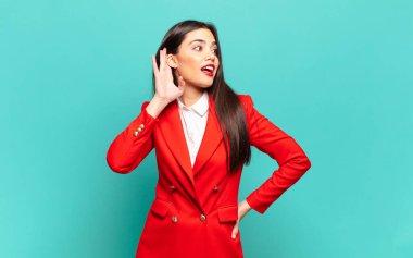 young pretty woman smiling, looking curiously to the side, trying to listen to gossip or overhearing a secret. business concept
