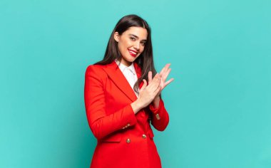 young pretty woman feeling happy and successful, smiling and clapping hands, saying congratulations with an applause. business concept
