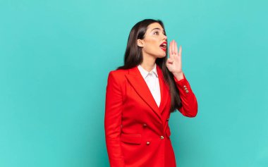 young pretty woman profile view, looking happy and excited, shouting and calling to copy space on the side. business concept
